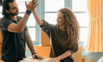 A person organizing their living room, surrounded by neatly packed boxes and items ready for storage. The scene is bright and tidy, reflecting the benefits of spring cleaning and decluttering.