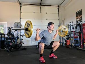 Man exercising in his garage, utilizing workout equipment and creating a home gym environment, showcasing an organized space for fitness and training.
